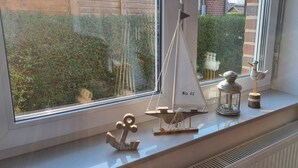 A window sill with a small sailboat model, a lantern, and a decorative anchor.