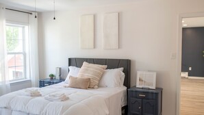 A bedroom with a bed, bedside tables, and artwork on the wall.