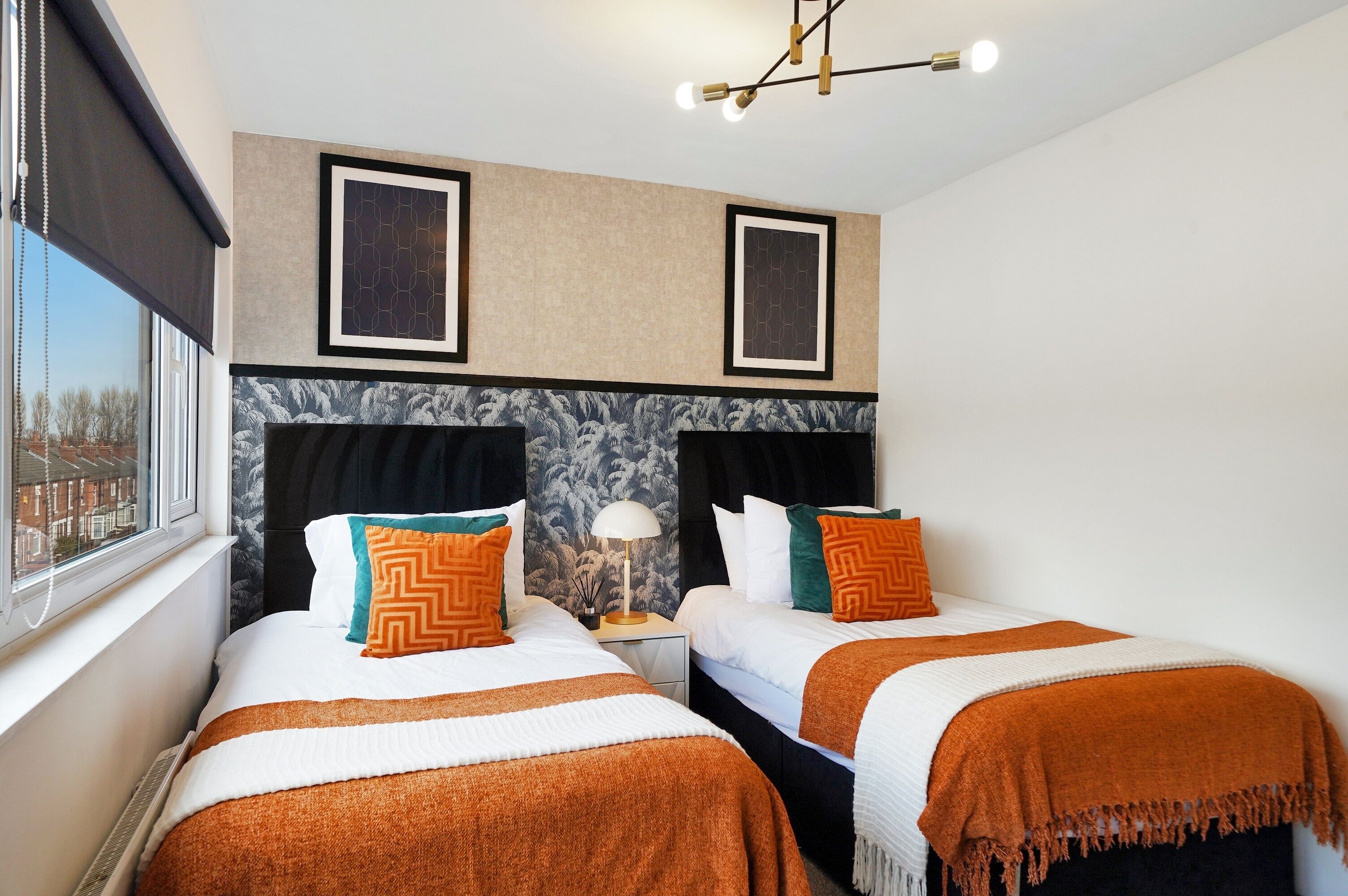 Une chambre d’hôtel avec deux lits, une grande fenêtre, une tête de lit en marbre et des œuvres d’art encadrées accrochées au mur.