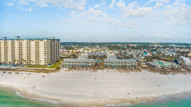 Un hotel costero con varias construcciones, una playa y cielo despejado.