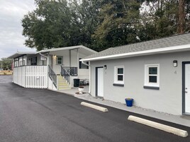 Une rangée de maisons mobiles blanches, avec des toits gris, chacune dotée d'une porte d'entrée, de fenêtres et d'un petit porche.
