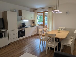 Una cocina moderna con armarios blancos, una mesa de comedor con sillas y vistas al exterior.