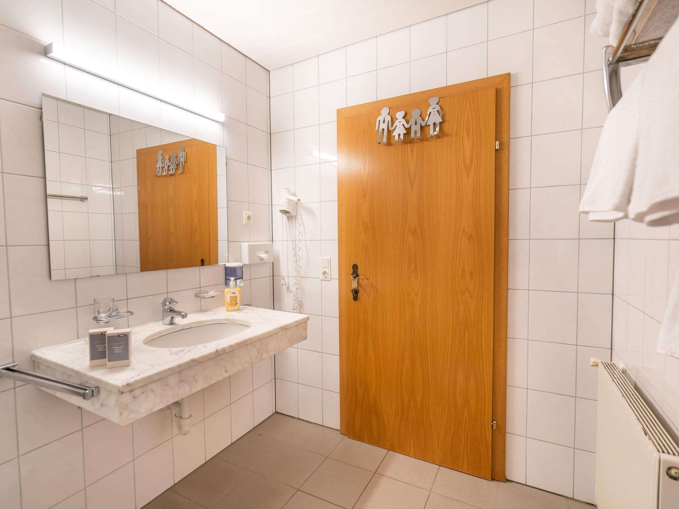 A bathroom with a marble sink, a wooden door, and a towel rack.