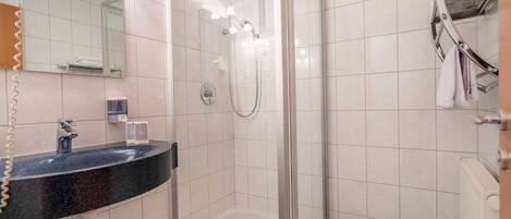 Une salle de bain moderne avec une douche à parois de verre, un lavabo noir avec un miroir au-dessus et un porte-serviettes avec des serviettes.