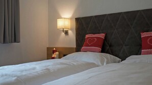 A hotel room with a bed, a nightstand, a wall-mounted lamp, and a window with curtains. - Flat Near the ski Area in Mayrhofen (Schwendau)