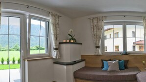 A room with a curved wooden bench, a small table with candles, and a view of a mountain landscape through large windows. - Flat Near the ski Area in Mayrhofen (Schwendau)