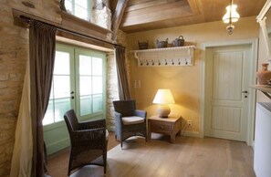 A cozy room with wicker chairs, a lamp, a shelf with baskets, and a door.