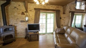 Una sala de estar acogedora con una pared de piedra, una chimenea, un sofá de cuero y un televisor.