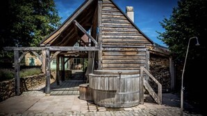 Una cabaña rústica de madera con cimientos de piedra, una escalera de madera y una estructura de barril de madera.