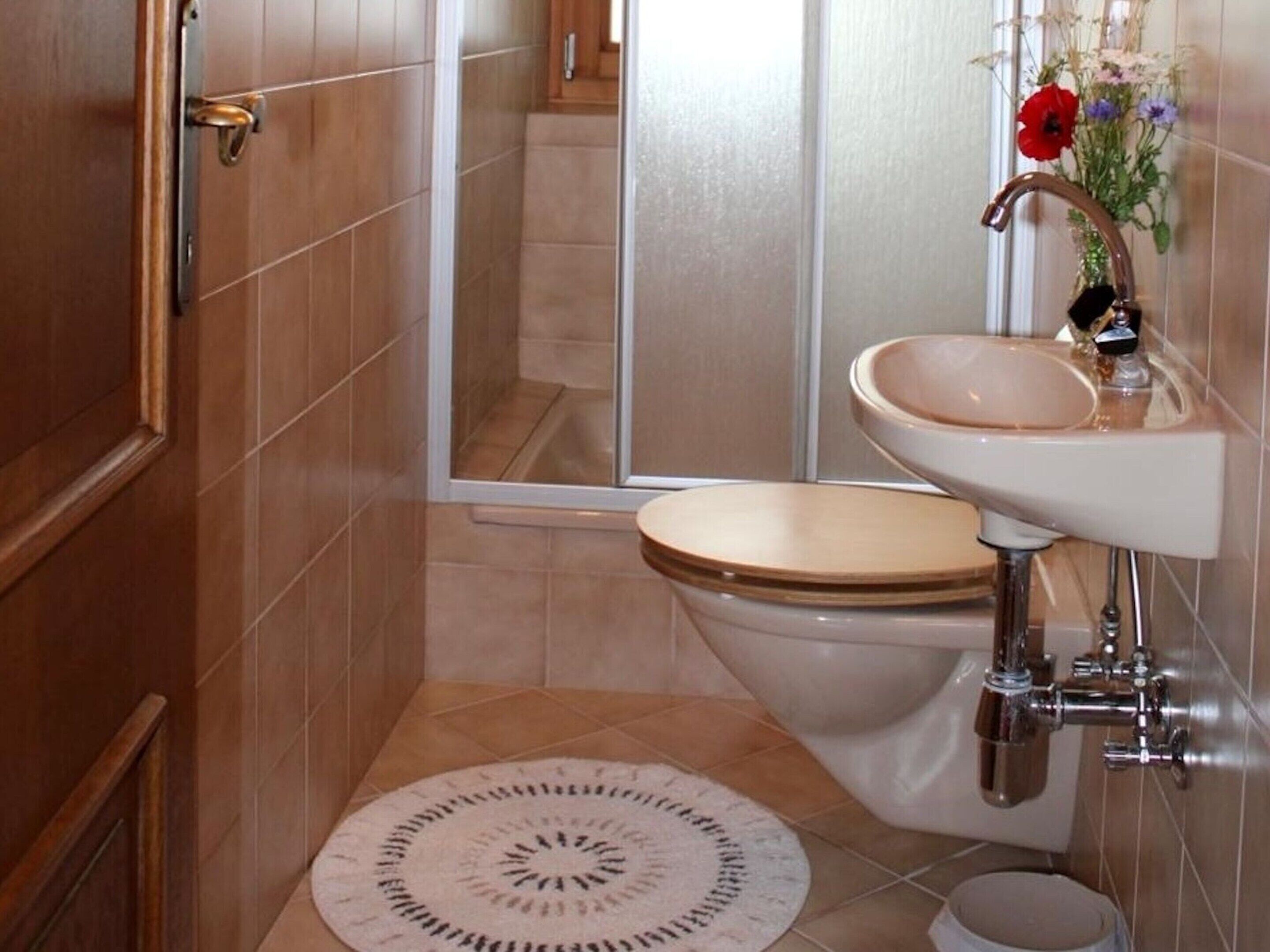 A bathroom with a toilet, sink, and mirror.