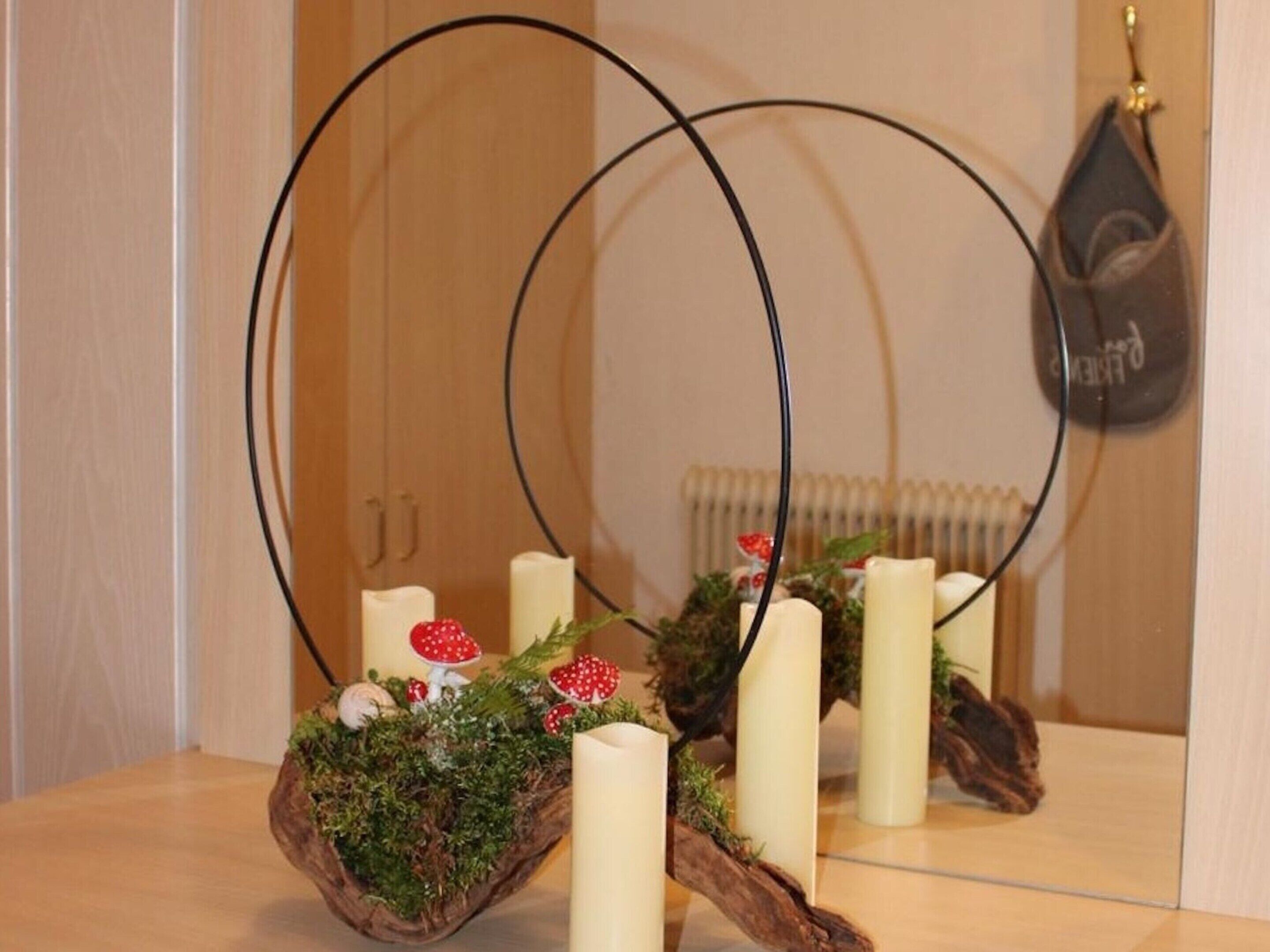 Un espejo que refleja un arreglo decorativo con velas y un centro de setas.