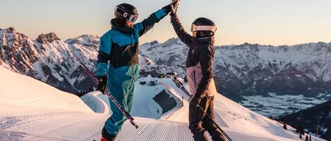 Two skiers high-fiving on a snowy slope with a mountain backdrop.