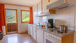 A kitchen with a large window, a built-in stove, and a coffee maker. - Apartment in Stubaital Near Ski Lift (Neustift Im Stubaital)