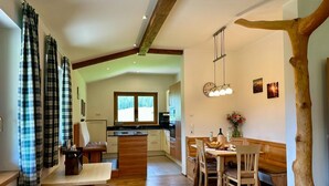 A modern kitchen with a central island, wooden flooring, and a dining area with a bench. - Apartment in Saalfelden am Steinernen Meer (Saalfelden am Steinernen Meer)