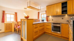 Une cuisine avec des meubles de rangement en bois, un four encastré et un coin repas comprenant une table et des chaises.