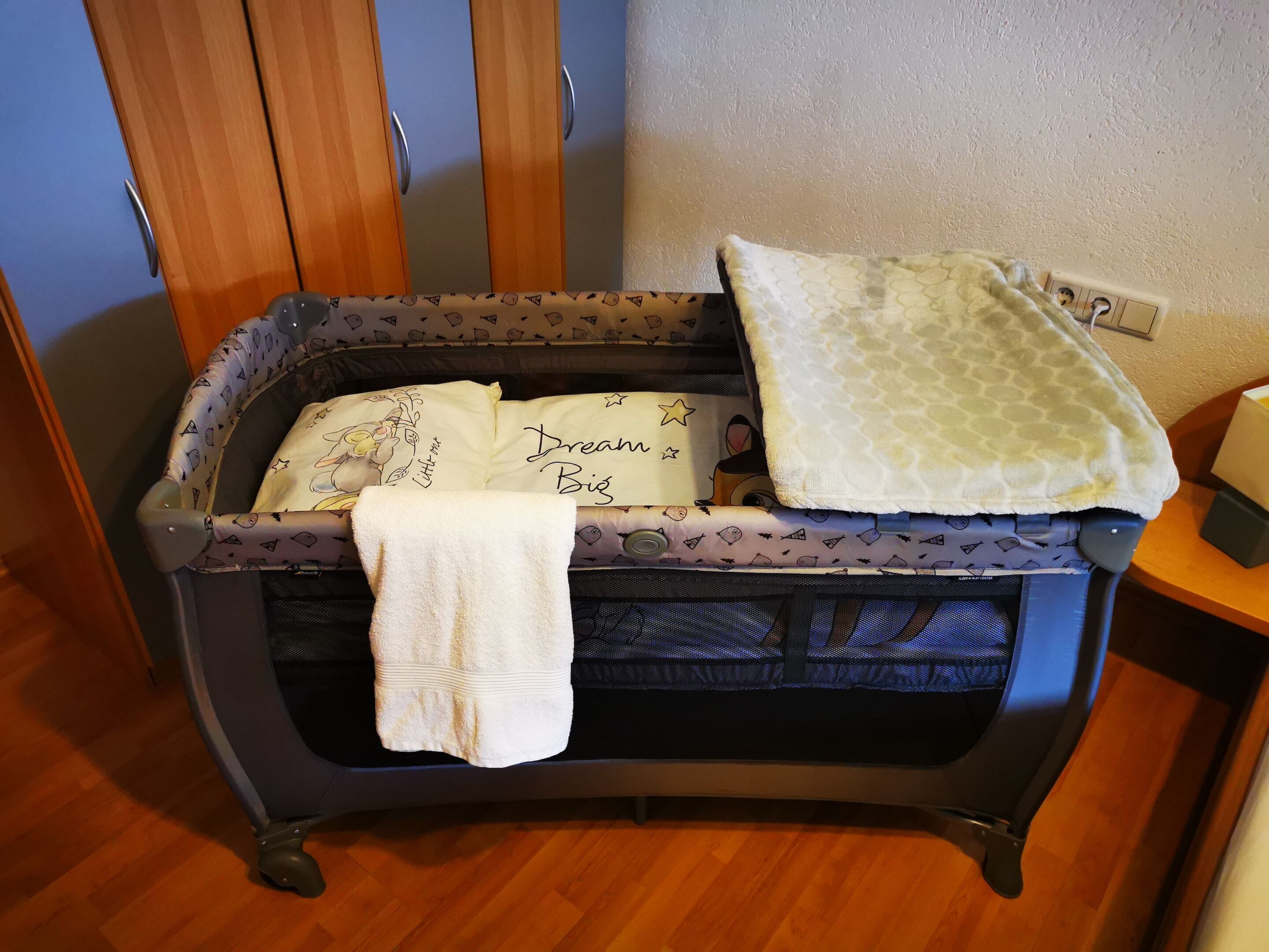 Un berceau pour bébé avec un matelas à motifs et une couverture blanche.