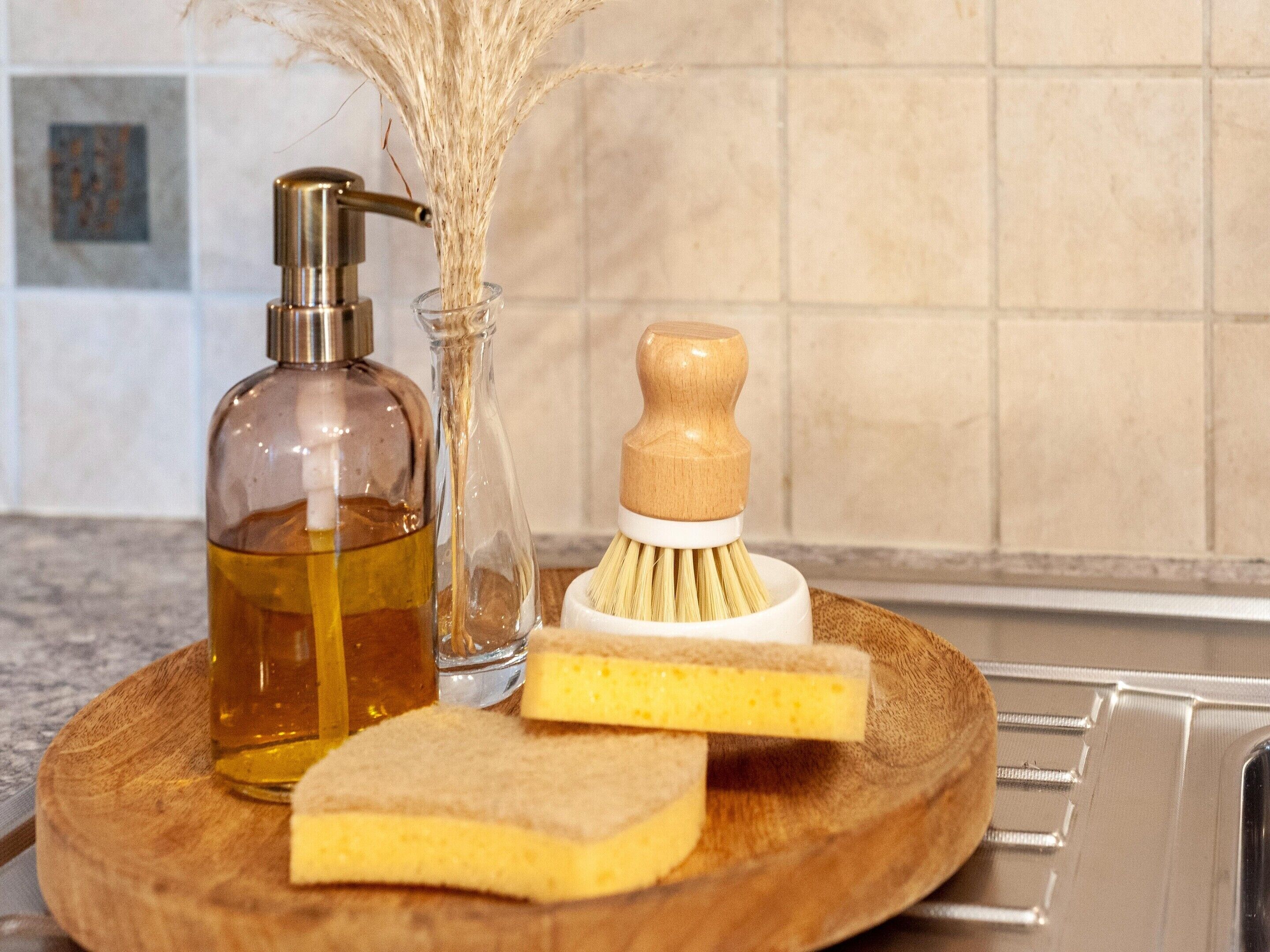 A wooden tray with a bottle of liquid soap, a wooden brush, and a sponge.