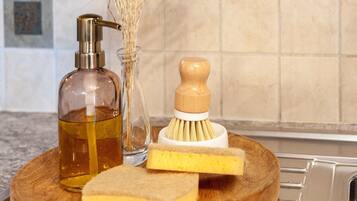 A wooden tray with a bottle of liquid soap, a wooden brush, and a sponge.