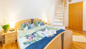 Une chambre à coucher avec un lit en bois, une table de chevet avec une lampe, un escalier et une porte en bois.