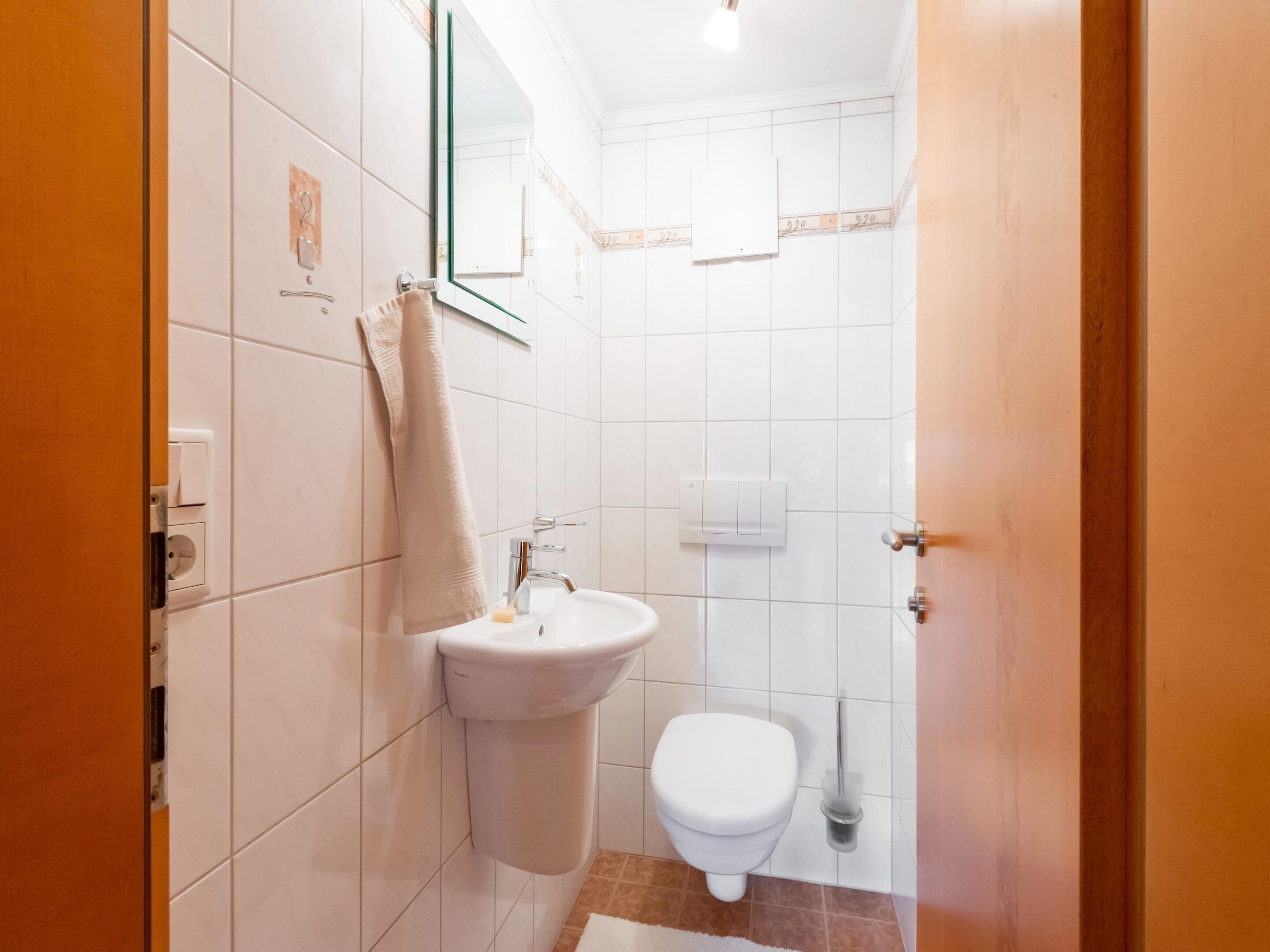 A small, clean bathroom with a sink, toilet, and mirror.