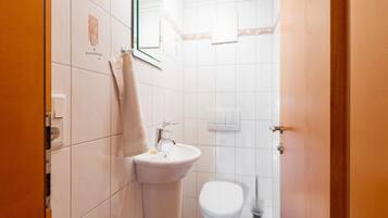 Un baño pequeño y limpio con lavamanos, inodoro y espejo.