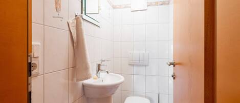 A small, clean bathroom with a sink, toilet, and mirror.