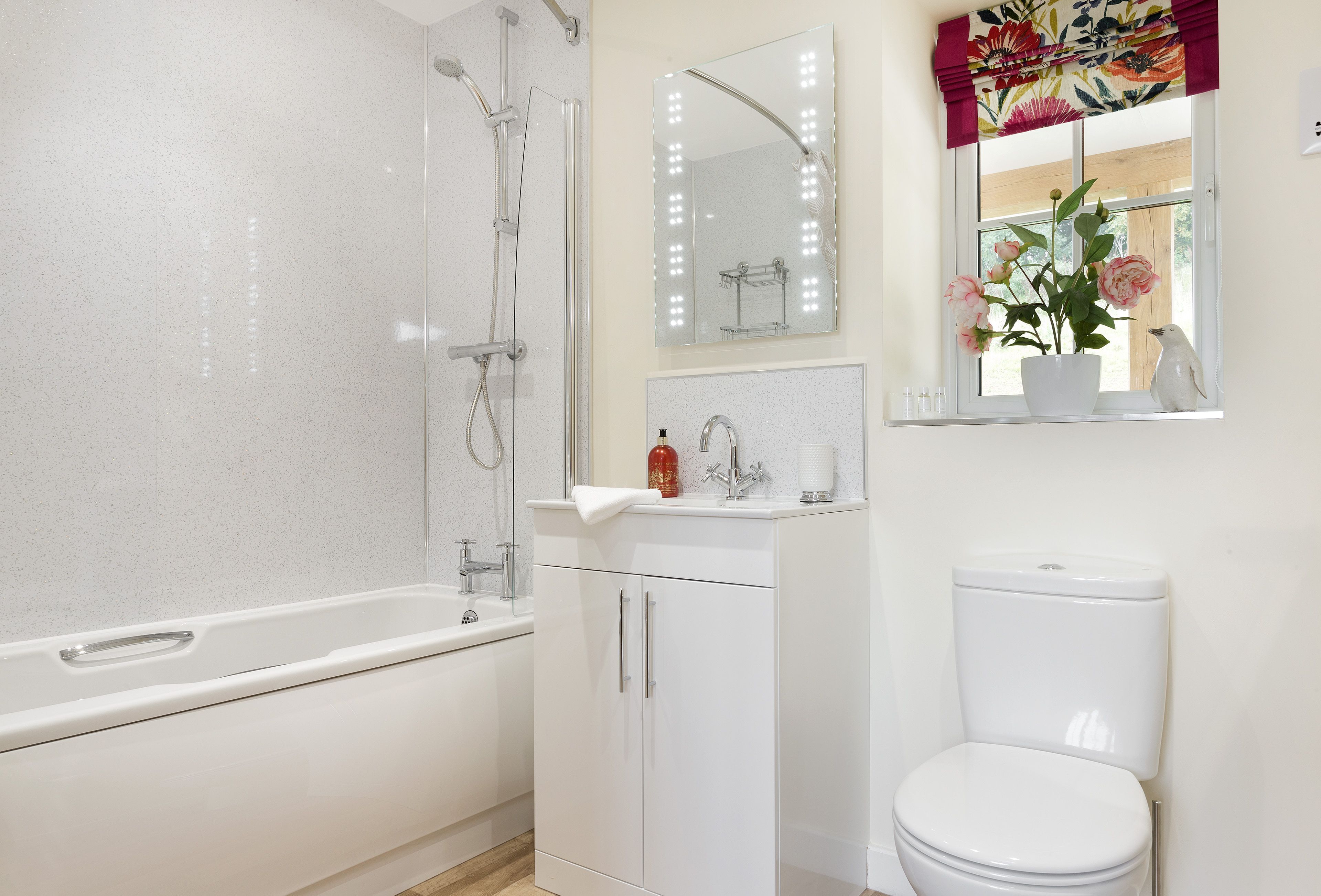 Un baño con bañera, inodoro, lavamanos y espejo con luces.