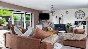 Ein Wohnzimmer mit einer Sofagarnitur, einem Kamin, einem Fernseher und einer Wanduhr.