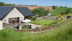 Ein Haus mit großem Garten, umzäunter Fläche und einer Solaranlage auf dem Dach.