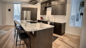 A modern kitchen with a marble countertop, stainless steel appliances, and dark cabinetry.
