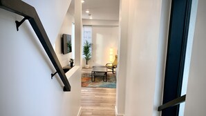 A modern staircase leading to a living area with a wooden floor, a sofa, and a lamp.