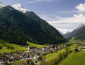 A mountain village with traditional architecture, a church, and a view of snow-capped mountains.