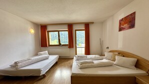 A hotel room with two single beds, a larger bed, a window with curtains, a radiator, and a painting on the wall. - Apartment Neustift Near Stubai Glacier (Neustift Im Stubaital)
