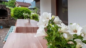 A patio area with a stone fireplace, wooden seating, and a potted plant with white flowers. - Moiklerhof Holiday Home in Ramsau im Zillertal (Ramsau im Zillertal)