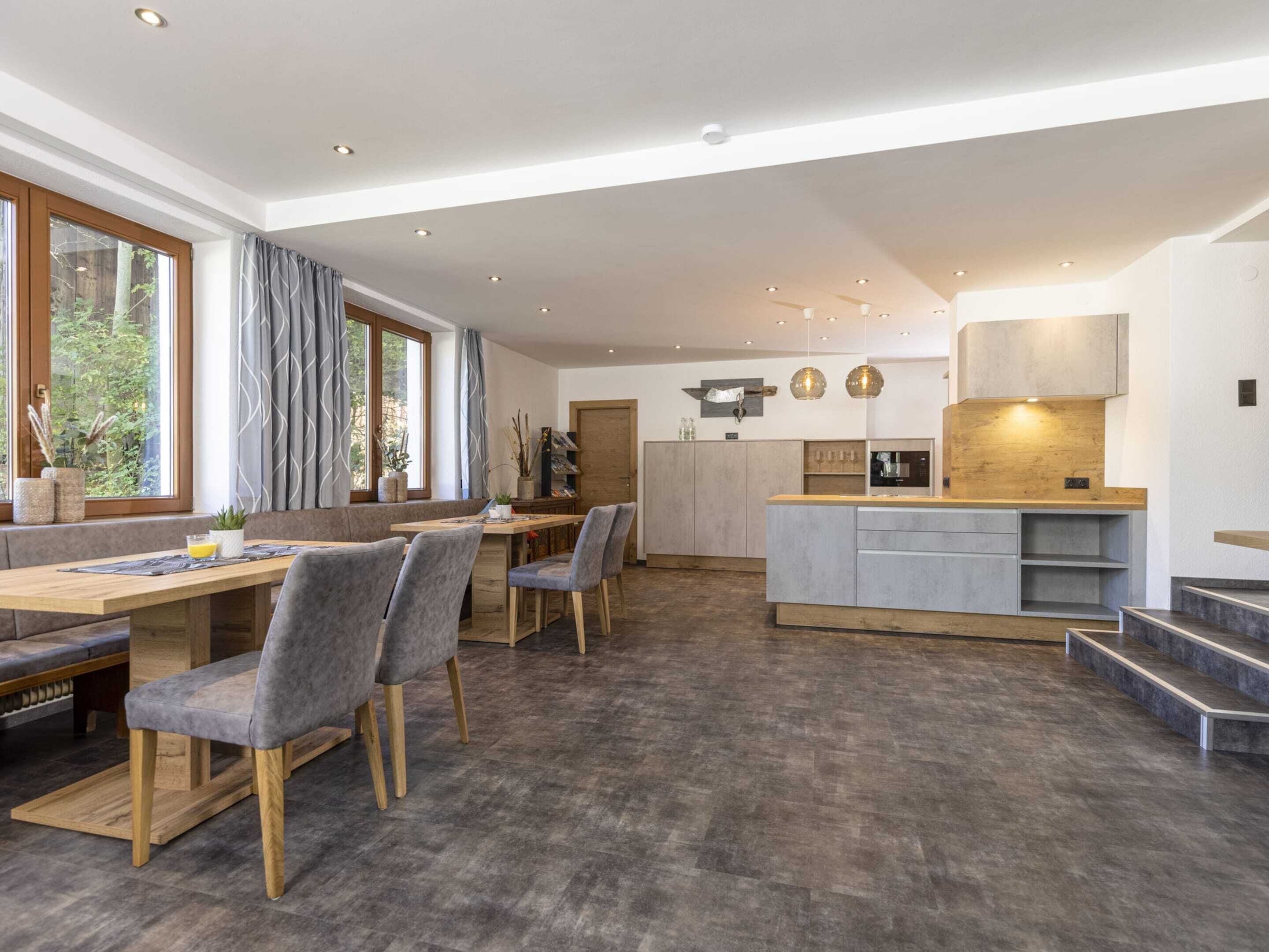Una cocina moderna con una isla central, suelo de madera e iluminación colgante.