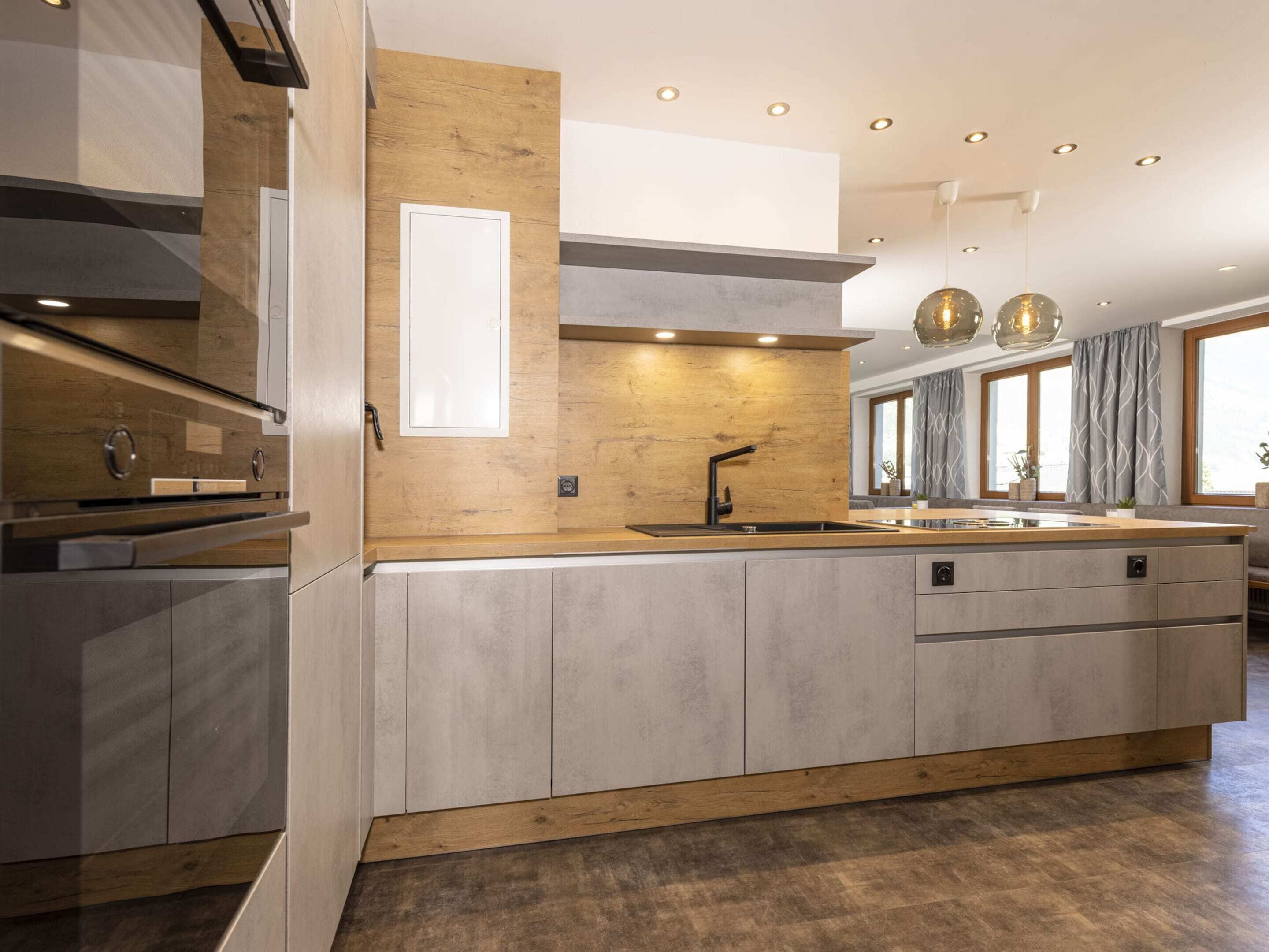 A modern kitchen with a central island, wooden cabinetry, and a built-in oven.