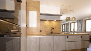 A modern kitchen with a central island, wooden cabinetry, and a built-in oven. - Moiklerhof Holiday Home in Ramsau im Zillertal (Ramsau im Zillertal)