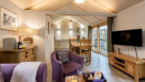 A cozy living room with a sofa, a TV, and a dining area with a table and chairs. - Lodge 19 (Wareham)