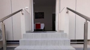 A set of marble stairs leading to an entrance with a closed shutter.