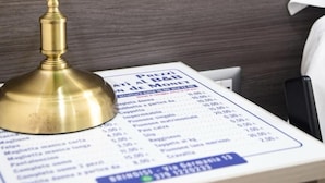 A green desk lamp with a brass base on a table with a printed menu.