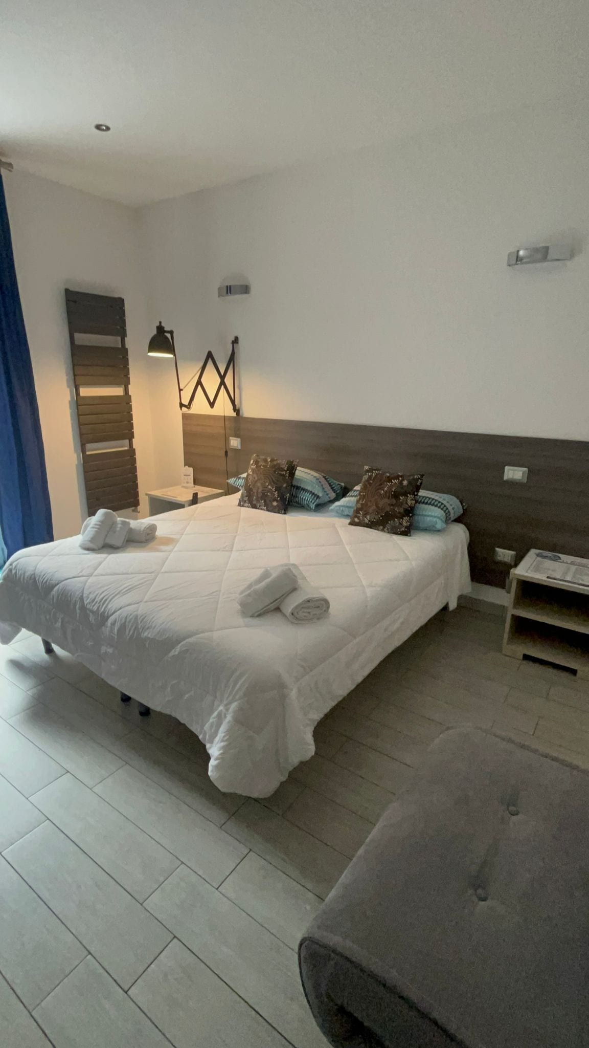 Une chambre d’hôtel moderne avec un grand lit, une table de chevet, une lampe et une tête de lit.