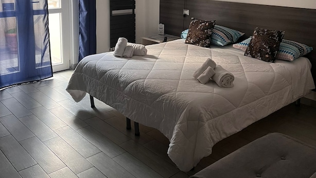 A modern bedroom with a large bed, a bedside table, a lamp, and a window with curtains.