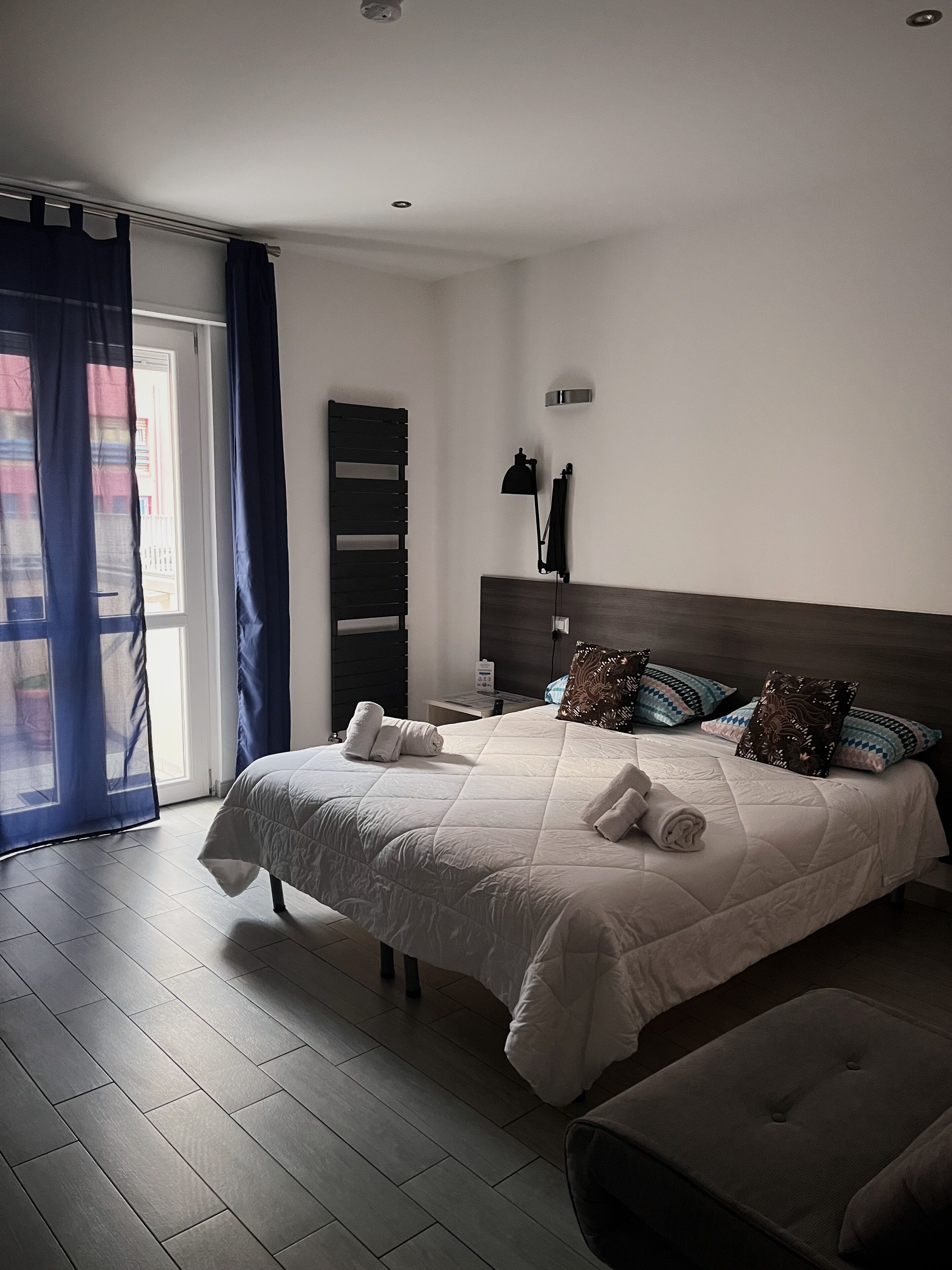 Un dormitorio moderno con una cama grande, mesitas de noche y un banco.