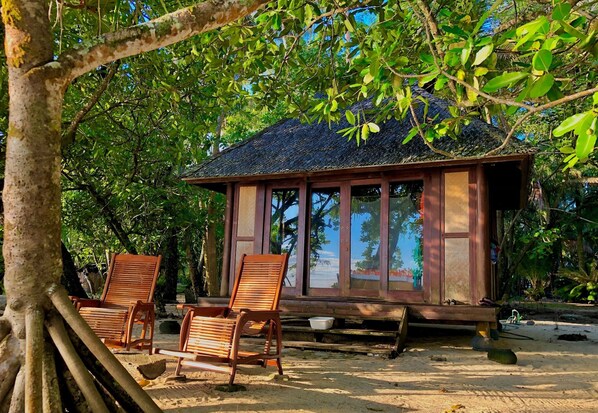 A wooden structure with large windows, two wooden chairs, and a bench.
