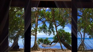 Vista al mar desde una ventana, con una hamaca y un banco.