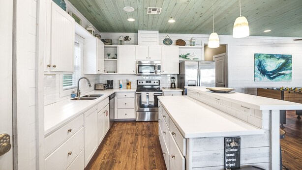 Una cocina moderna con armarios blancos, electrodomésticos de acero inoxidable y suelo de madera.