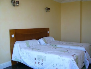 A double bed with floral bedding in a room with beige walls and a wooden headboard. - Arcachon Centre Front de mer Appartement120m2 Avec une Grande Terrasse Privative (Arcachon)