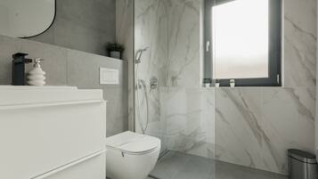 A modern bathroom with a toilet, sink, and shower area.