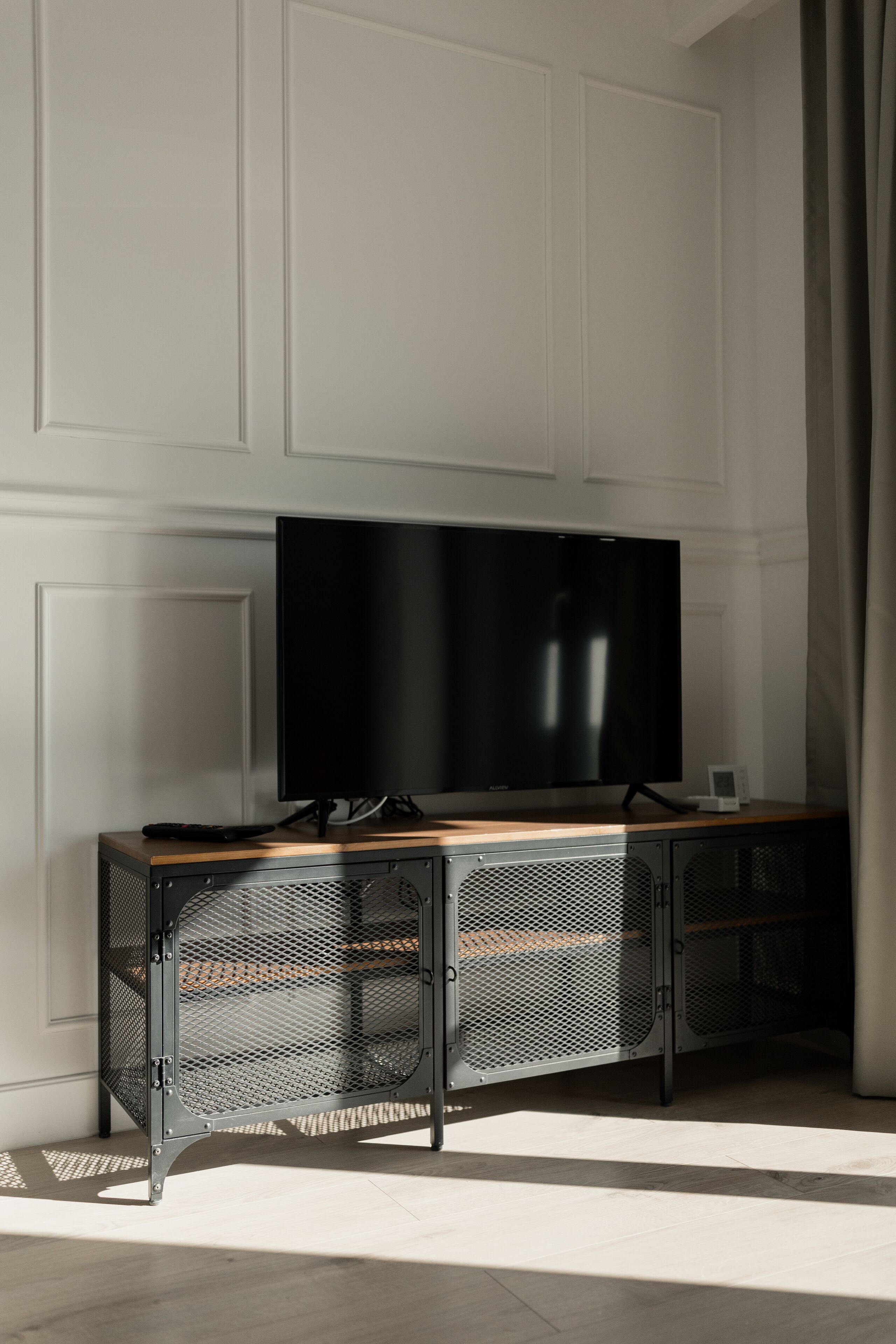 Uma sala de estar moderna com uma televisão de tela plana presa a um armário de madeira com portas de malha.