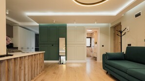 A modern kitchen with a wooden island, a green sofa, and a hallway leading to a bathroom. - Nest Inn Meteor (Cluj-Napoca)